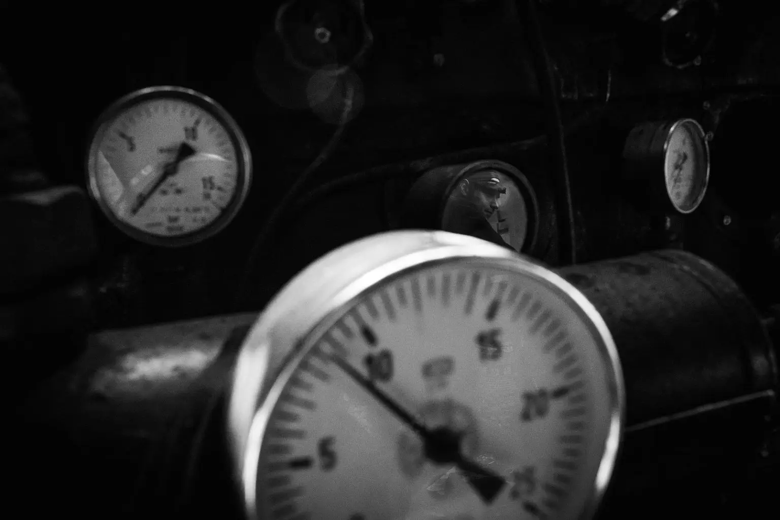 Primer plano en blanco y negro de varios manómetros e instrumentos de presión de maquinaria ferroviaria.
