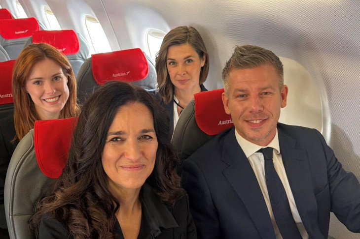 Péter Magyar y Anita Orbán sentados con su delegación a bordo de un avión de Austrian Airlines