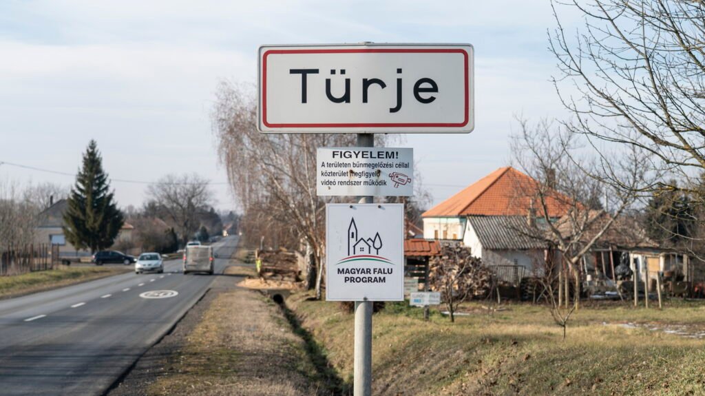 Señal de entrada a Türje junto a una carretera, con el distintivo del Magyar Falu Program