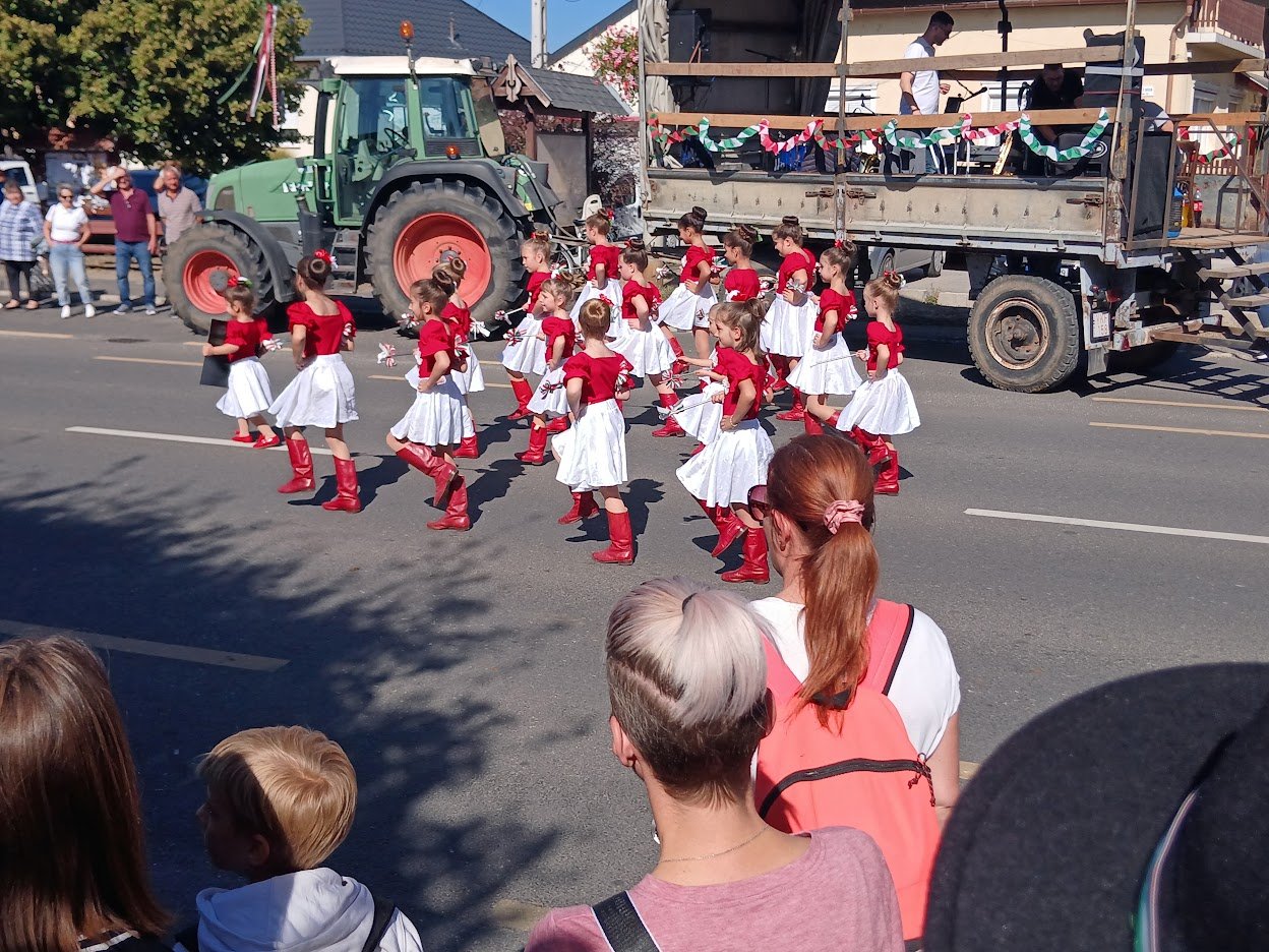 Niños con trajes tradicionales bailan junto a un tractor