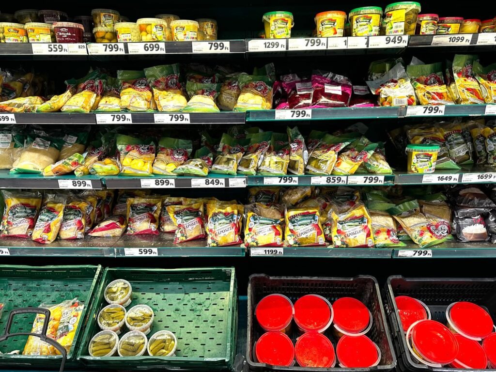 Estantería de encurtidos, chucrut y verduras preparadas con precios en forintos en un supermercado de Budapest