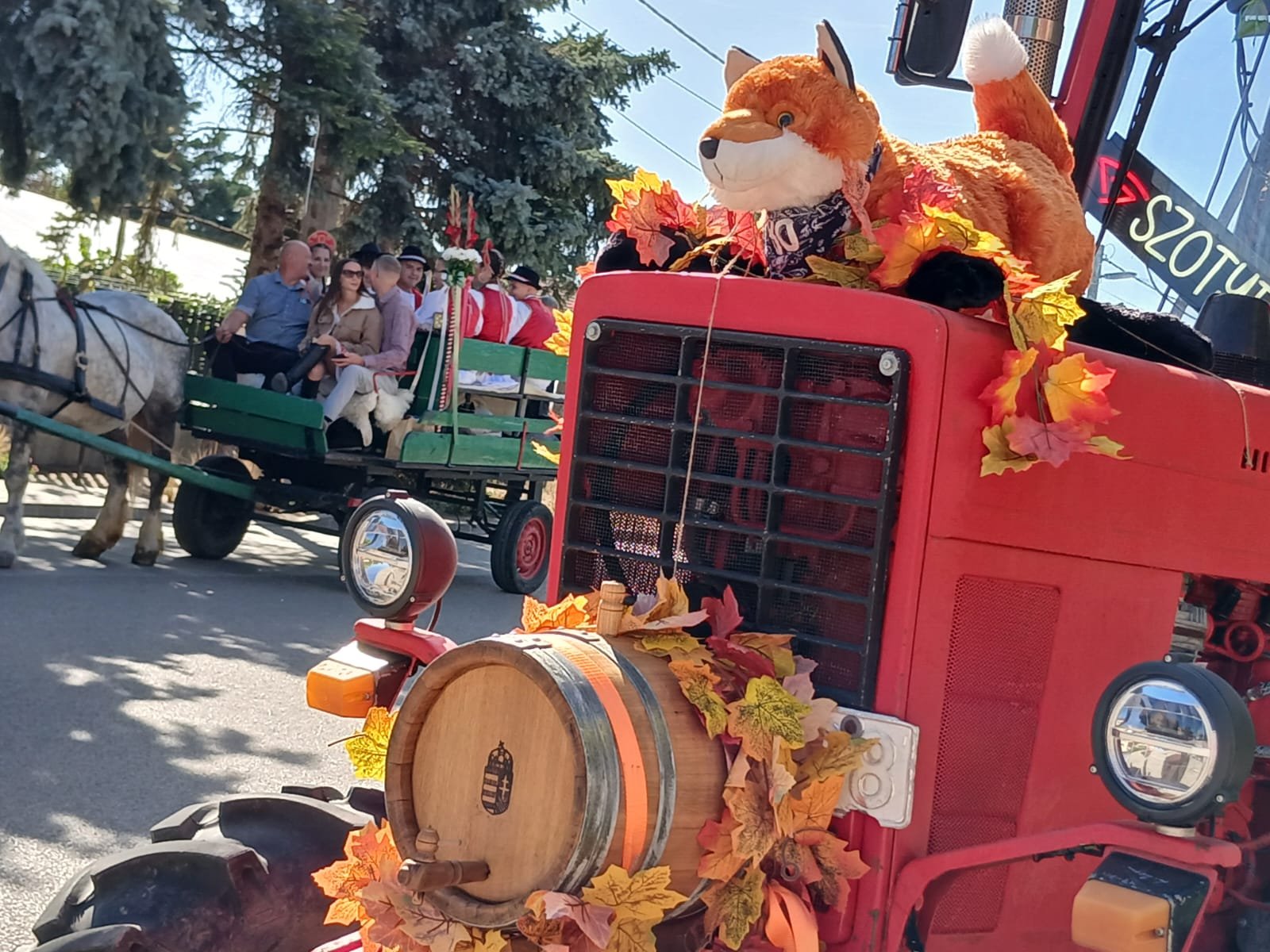 Tractor rojo decorado con hojas otoñales, un barril y un zorro de peluche