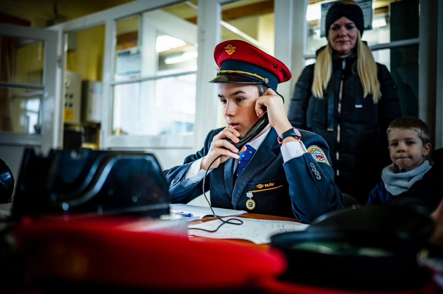 Joven ferroviario del Gyermekvasút atendiendo el teléfono en una estación
